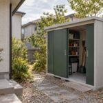 住宅脇の通路から、引戸を開けた庭の物置へ近づく場面
