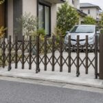 住宅の車庫前を閉じた伸縮門扉と、奥に停めた乗用車